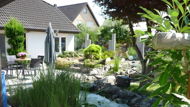 A garden with a pond, rocks, and a chair. - Apartment 'Carpe Diem' with Shared Terrace, Shared Garden and Wi-Fi (Rust)