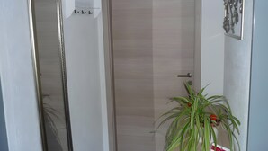 A door with a handle, a mirror, a wall-mounted light fixture, and a potted plant. - Apartment 'Carpe Diem' with Shared Terrace, Shared Garden and Wi-Fi (Rust)