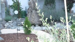 A garden with a rock formation, a small tree, and a metal pole. - Apartment 'Carpe Diem' with Shared Terrace, Shared Garden and Wi-Fi (Rust)