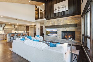 A spacious living area with a fireplace, a large sofa, and a television mounted above it.