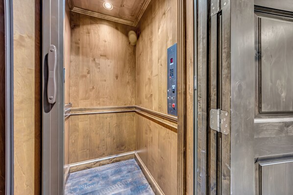 An elevator with wooden walls and a metal control panel.