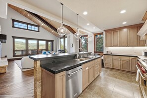 A spacious kitchen with a large island, wooden cabinets, and a view of the outdoors.