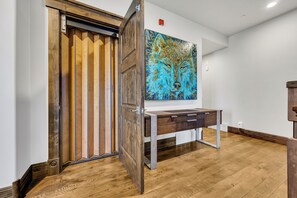 A room with a wooden floor, a desk with drawers, and a large painting of a wolf's face on the wall.