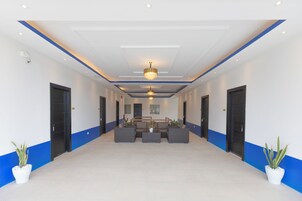 A spacious lobby with a central seating area, a chandelier, and potted plants.
