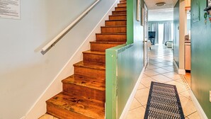 A wooden staircase with a handrail, a green door, and a tiled floor.