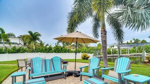 Une terrasse extérieure avec des fauteuils Adirondack, une table et un parasol.