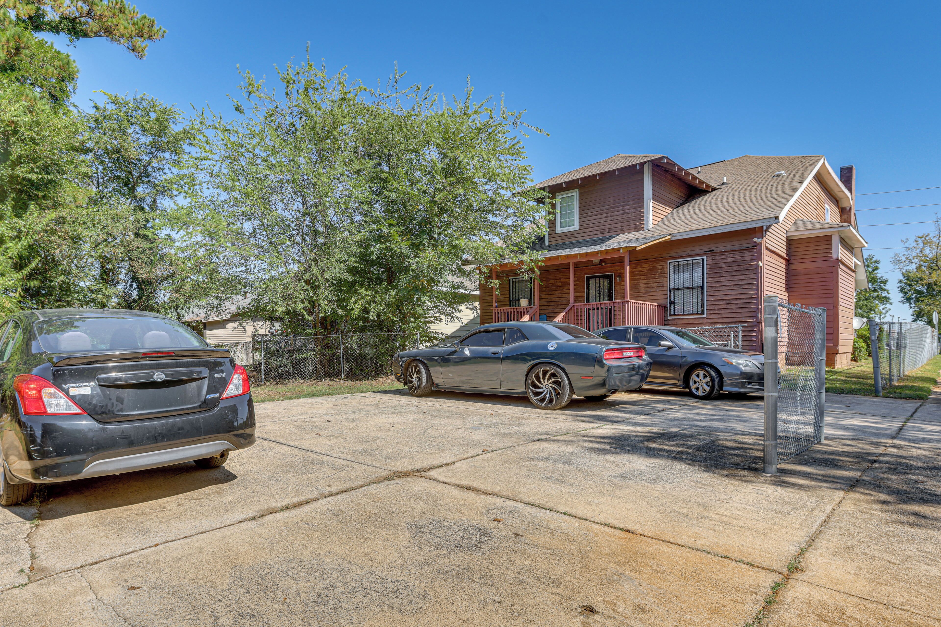A two-story house with a garage, two cars parked in the driveway, and a clear blue sky.