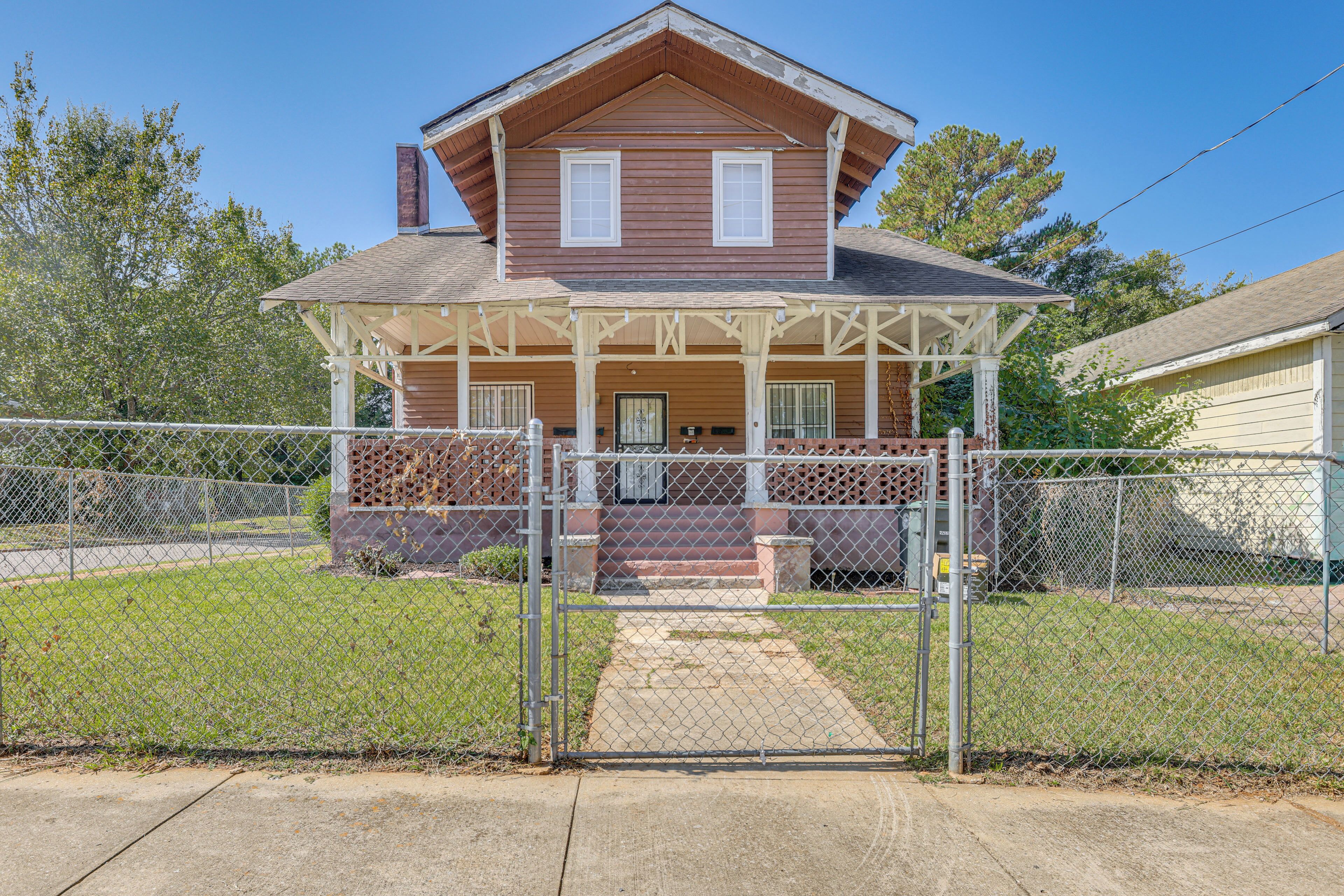 A two-story house with a porch and a fenced yard.