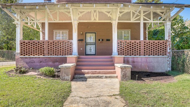 Une maison à deux étages avec un porche couvert, une porte d’entrée et un petit jardin à l’avant.