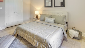 Une chambre à coucher avec un lit, une table de chevet, une lampe et un panier en osier gris.