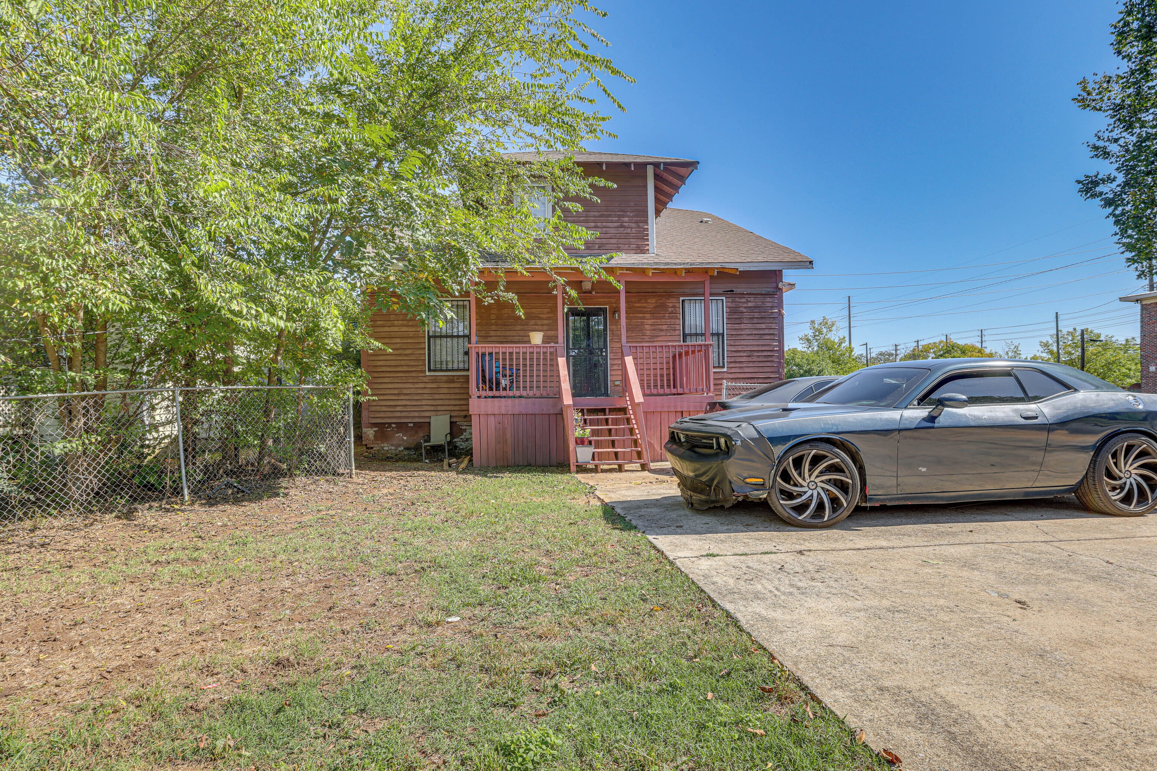 A two-story house with a covered porch and a car parked in the driveway.