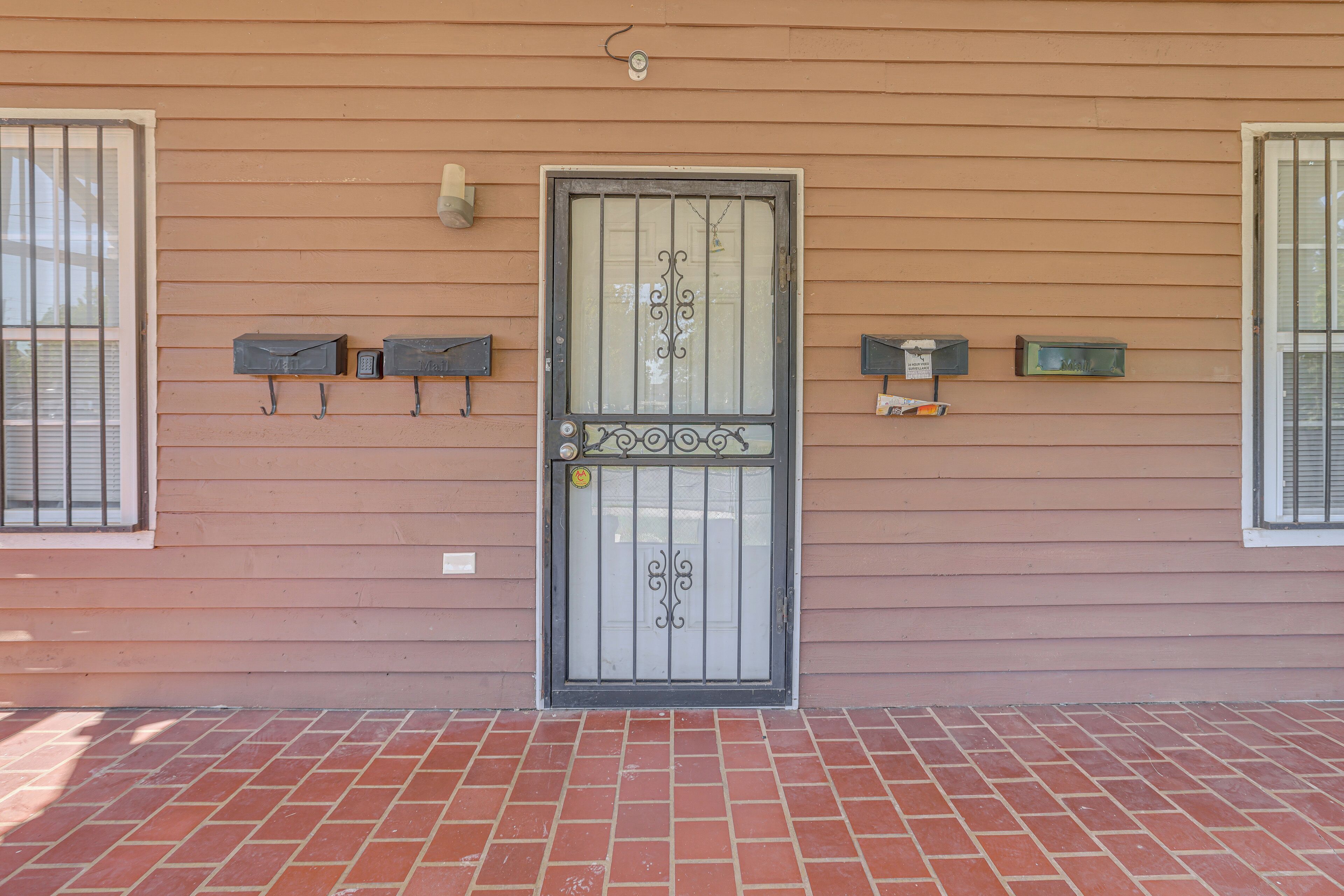 Una casa con un'ampia porta doppia, due cassette postali e un pavimento in mattoni.