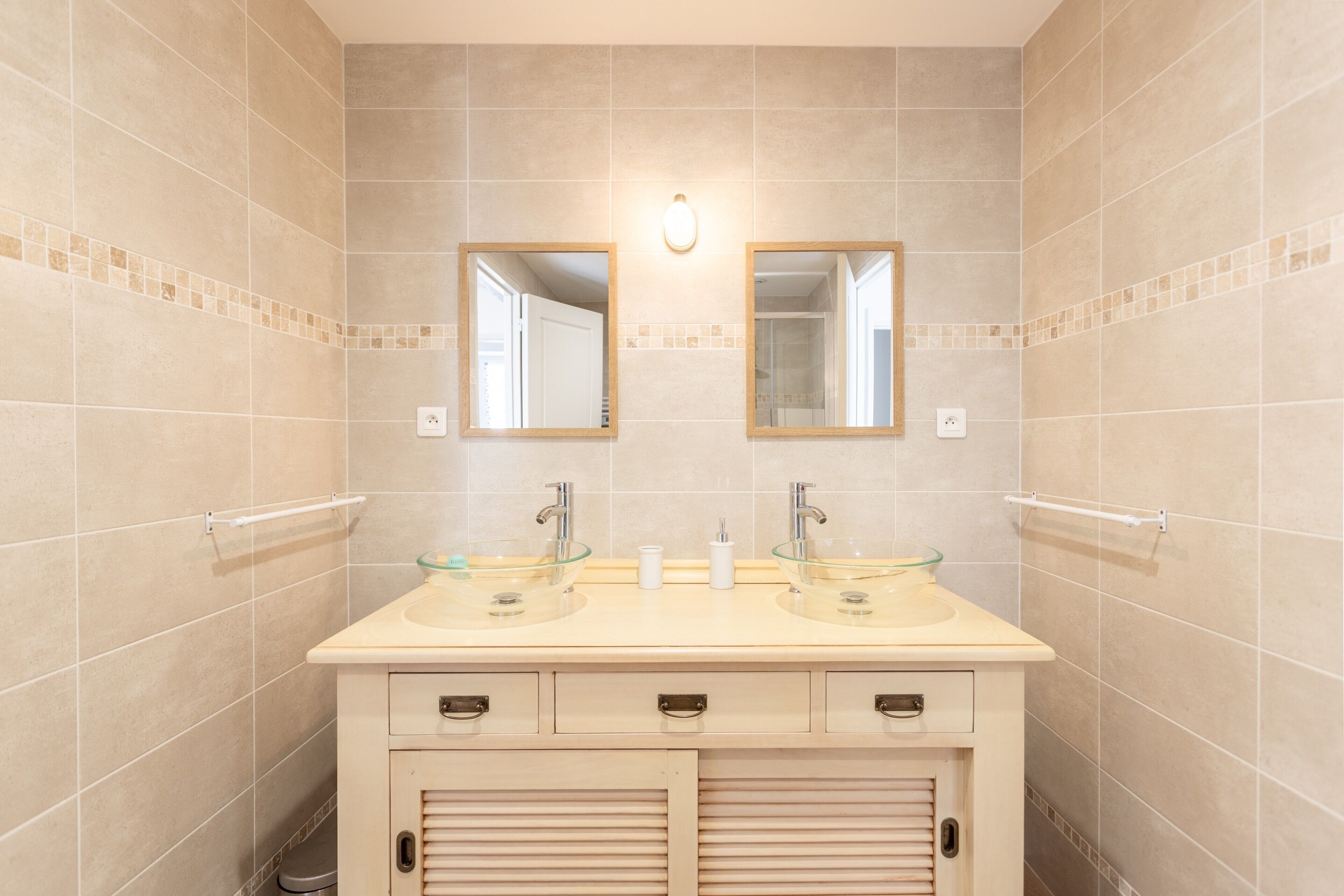 Un baño con dos lavamanos, un espejo y una lámpara.