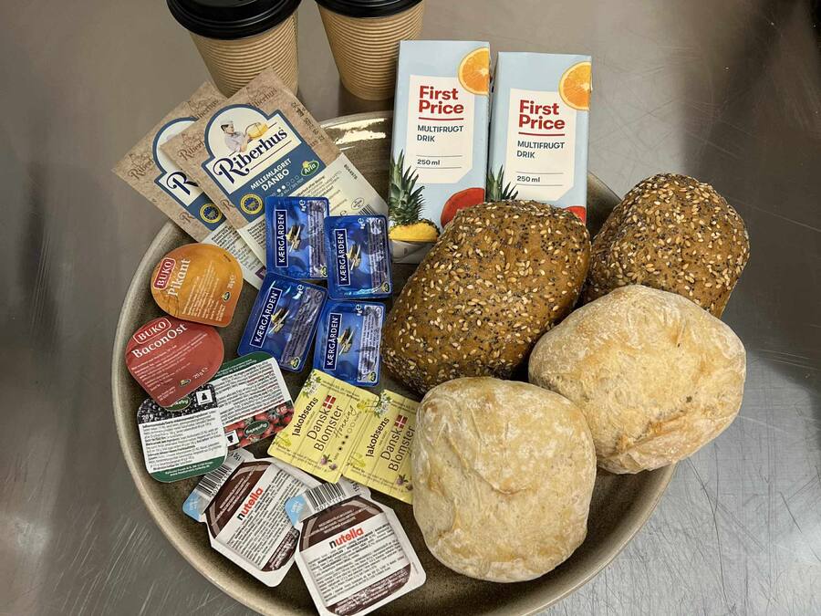 Una bandeja con diversos alimentos, incluyendo pan, bocadillos envasados y una caja de jugo.