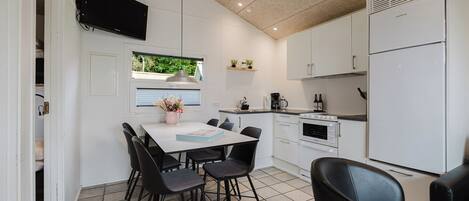 A compact kitchen with white cabinets, a built-in oven, and a white refrigerator.