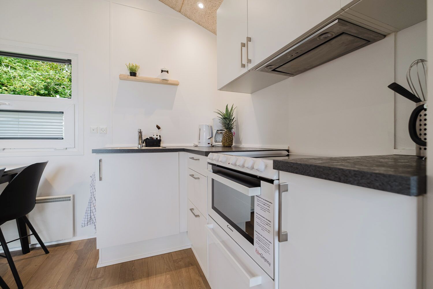 Een kleine keuken met witte kasten, een inbouwoven en een werkblad.