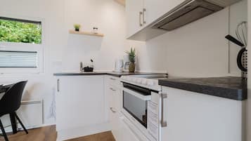 Een kleine keuken met witte kasten, een inbouwoven en een werkblad.