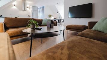Una sala de estar moderna con sofás marrones, una mesa redonda de centro y un televisor de pantalla plana montado en la pared.