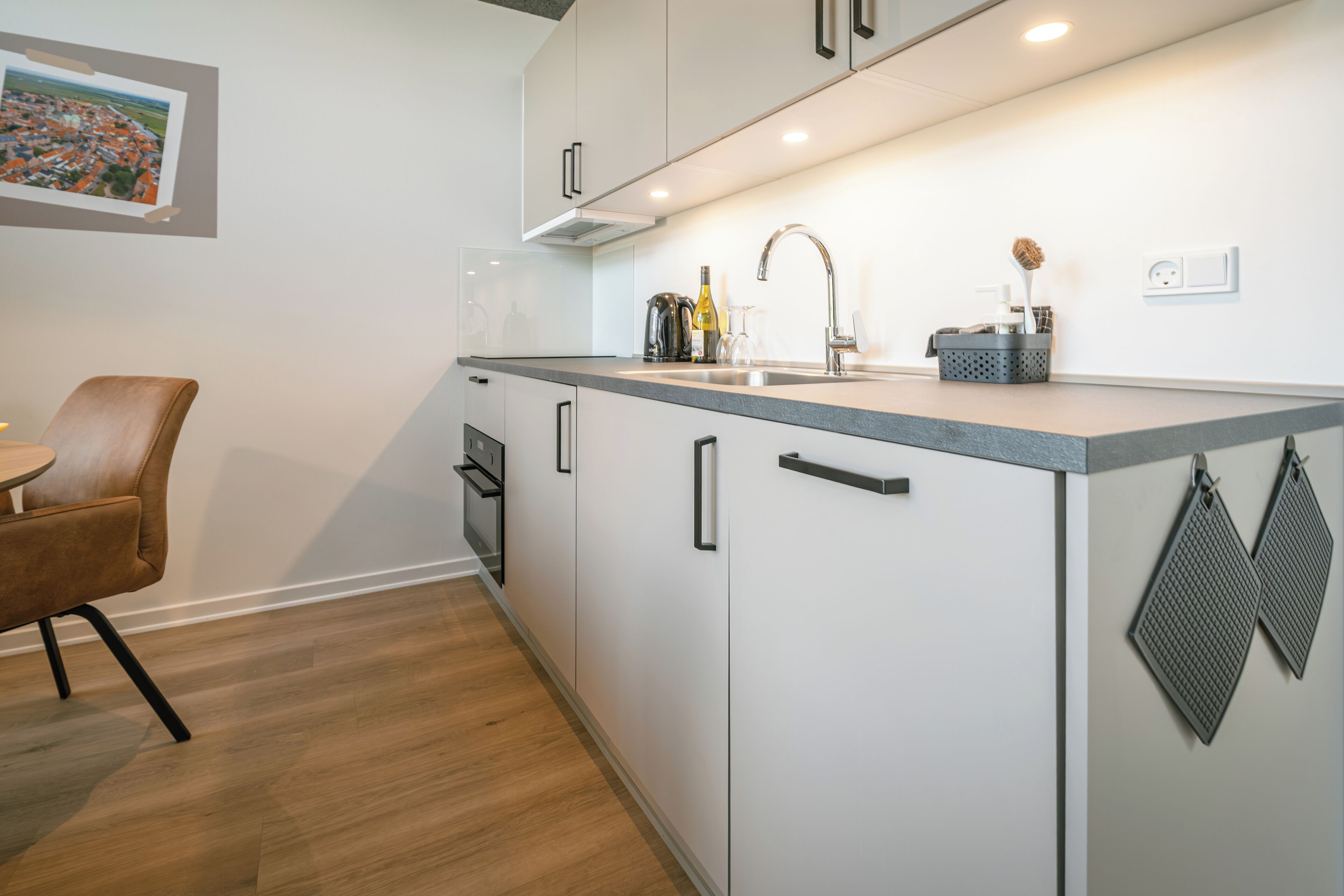 Una cocina moderna con armarios blancos, encimera de granito y pileta de acero inoxidable.