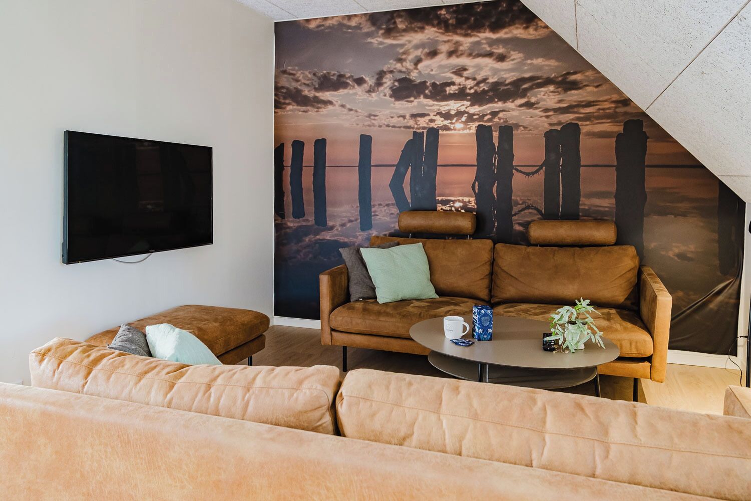 Una sala de estar moderna con un sofá grande, una mesa de centro y un televisor instalado en la pared.