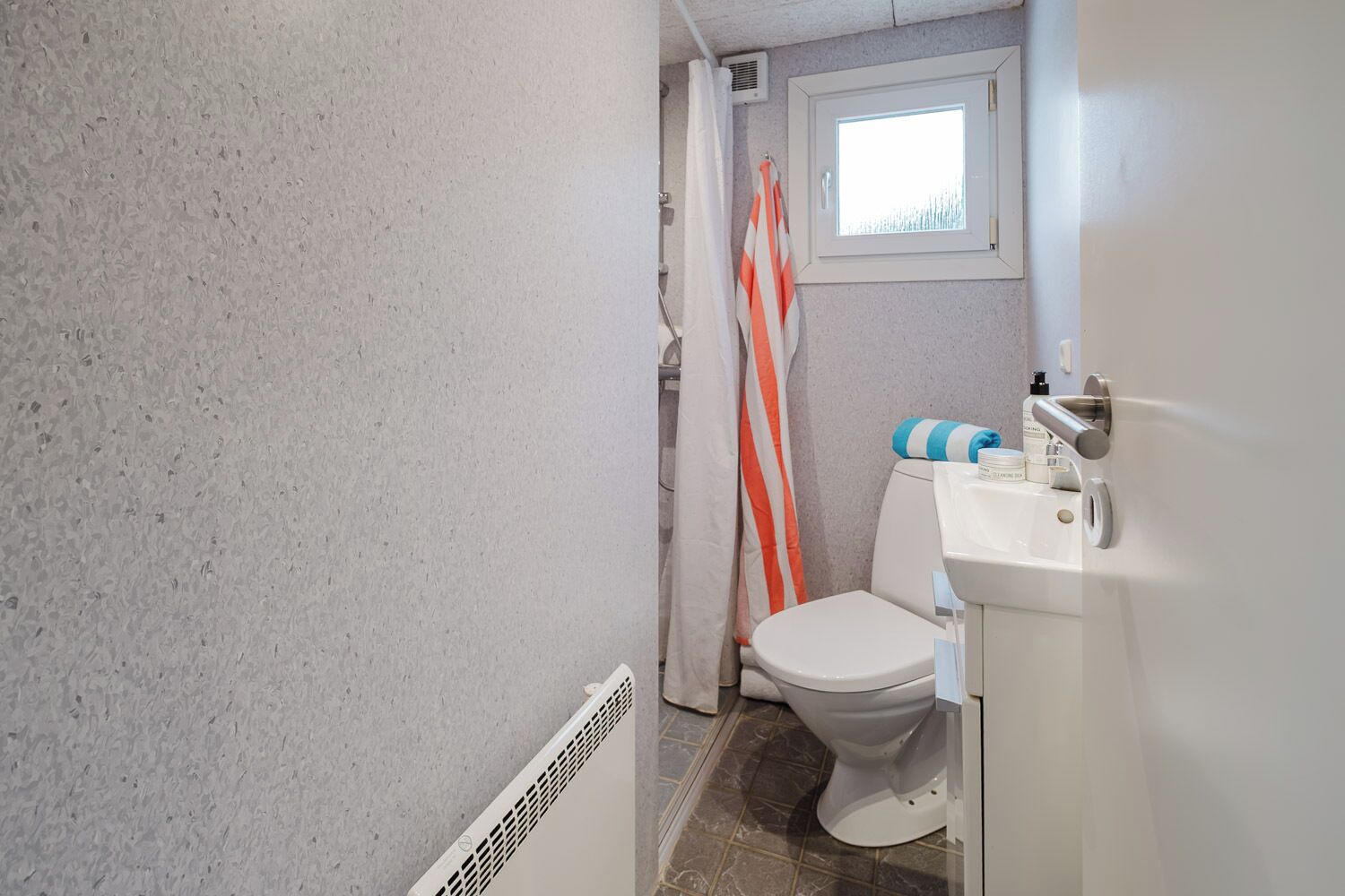 A bathroom with a toilet, sink, and shower area.