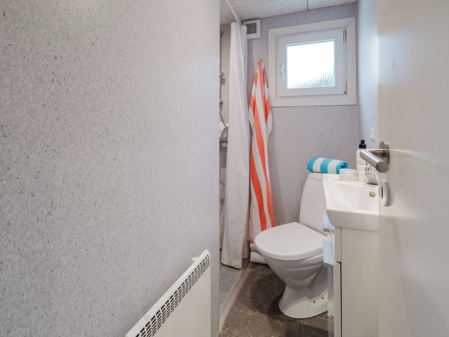 A bathroom with a toilet, sink, and shower area.