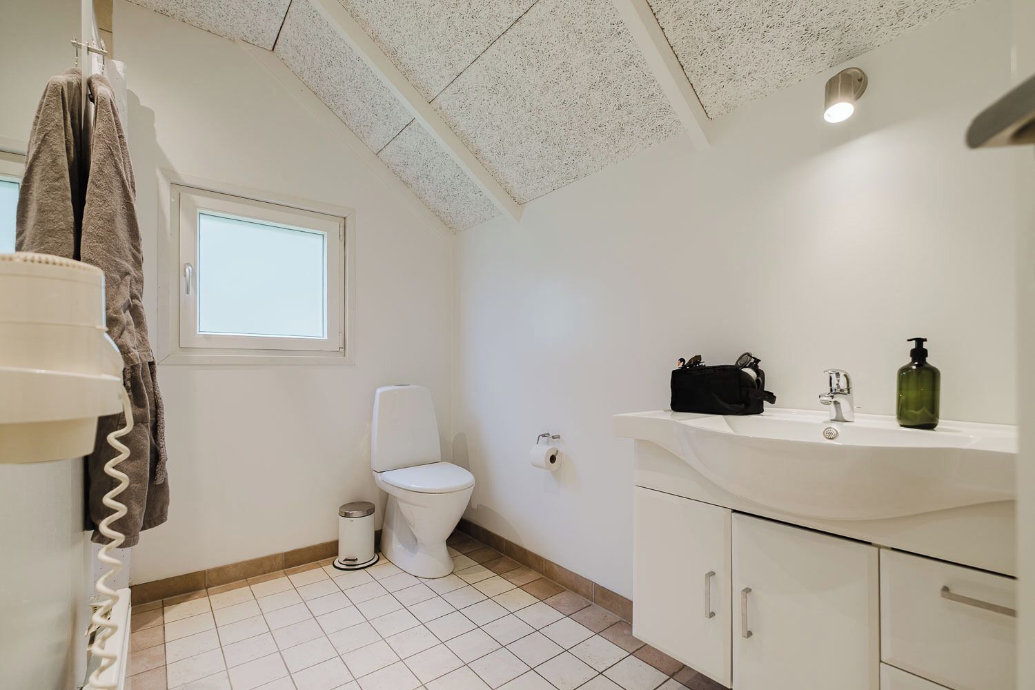 Ein Badezimmer mit Toilette, Waschbecken mit Spiegel und Handtuchhalter.