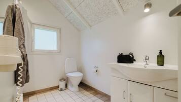 A bathroom with a toilet, a sink with a mirror, and a towel rack.