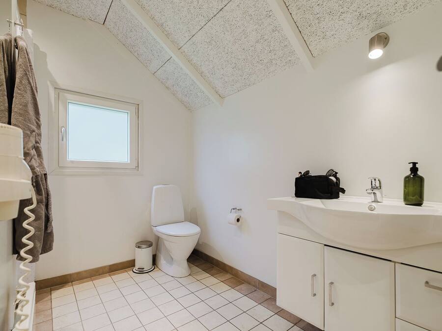 A bathroom with a toilet, a sink with a mirror, and a towel rack.