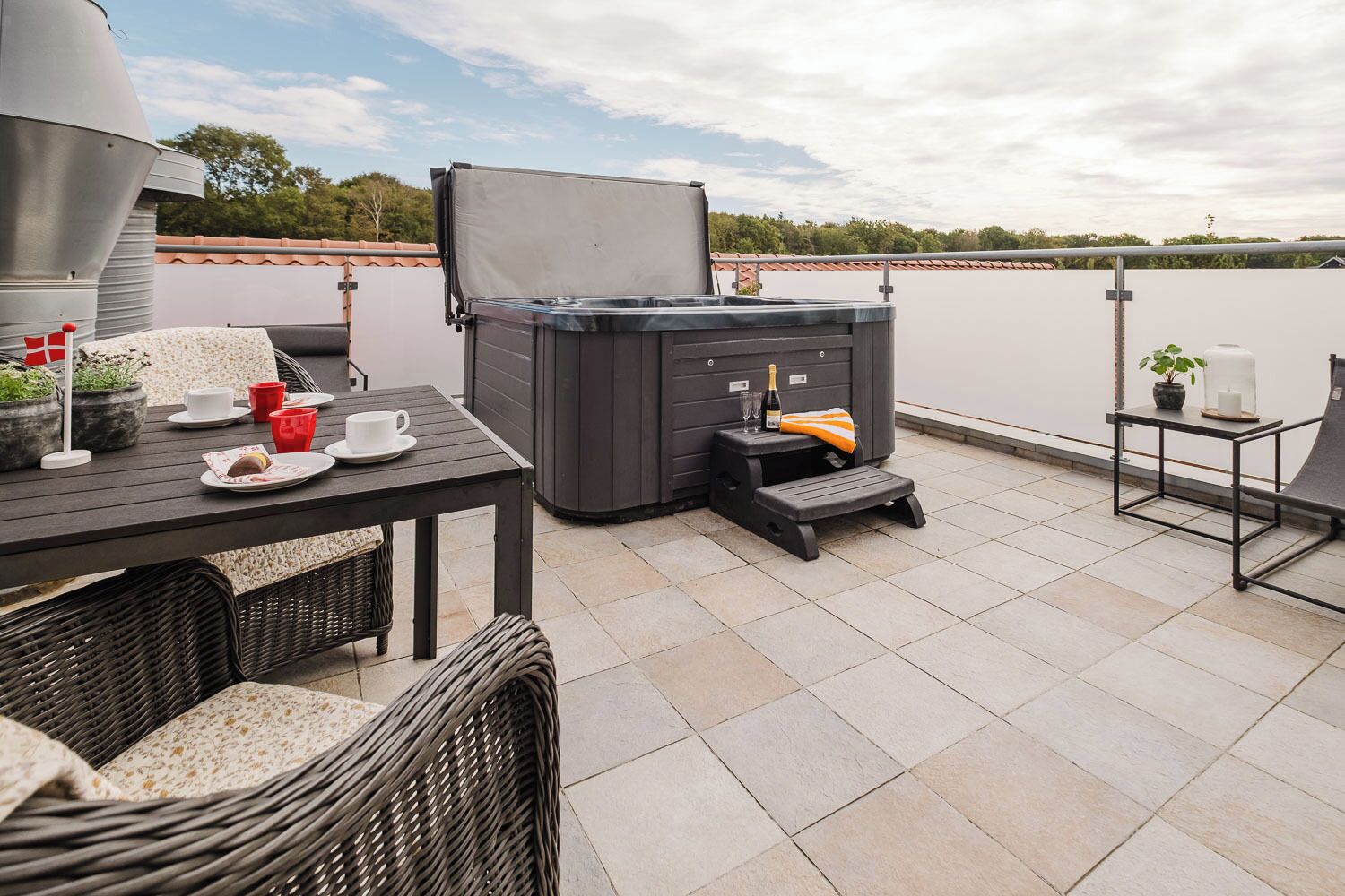 A rooftop terrace with a table, chairs, a small heater, and a water tank.