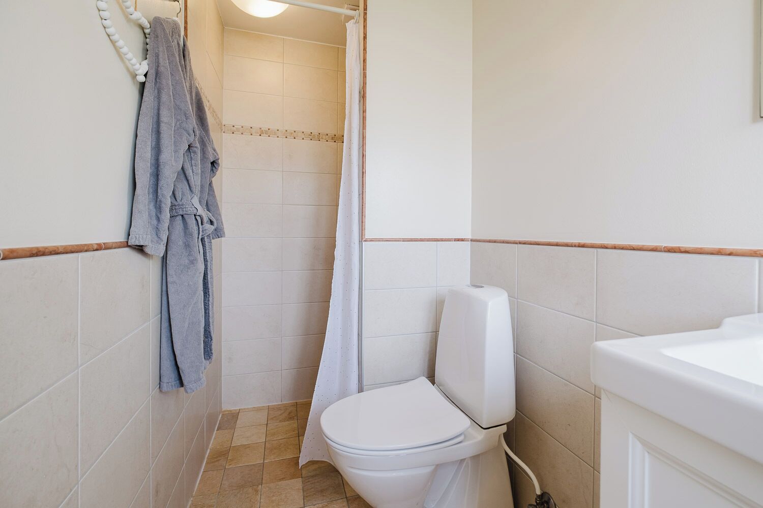 Une salle de bain équipée de toilettes, d’un rideau de douche et d’un porte-serviettes avec une serviette.