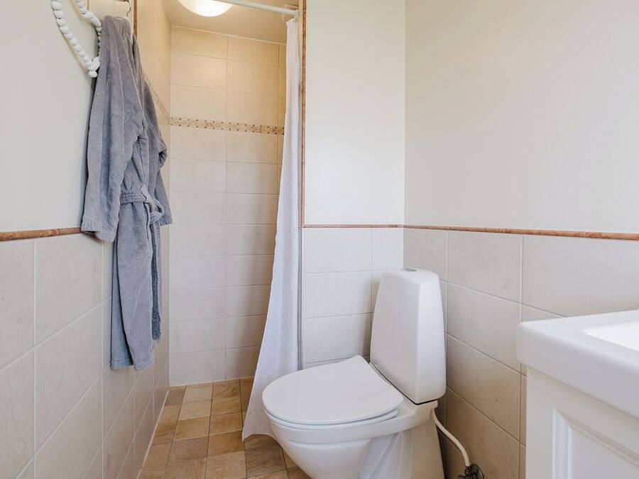 Un baño con inodoro, cortina de ducha y toallero con toalla.