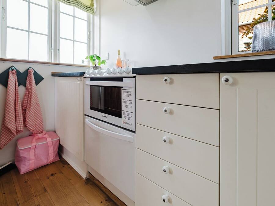 A kitchen with white cabinets, a built-in oven, and a window with a view of greenery outside.