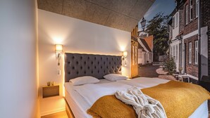 A neatly made bed with a tufted headboard, two bedside lamps, and a throw blanket. - Ribe Camping (Ribe)