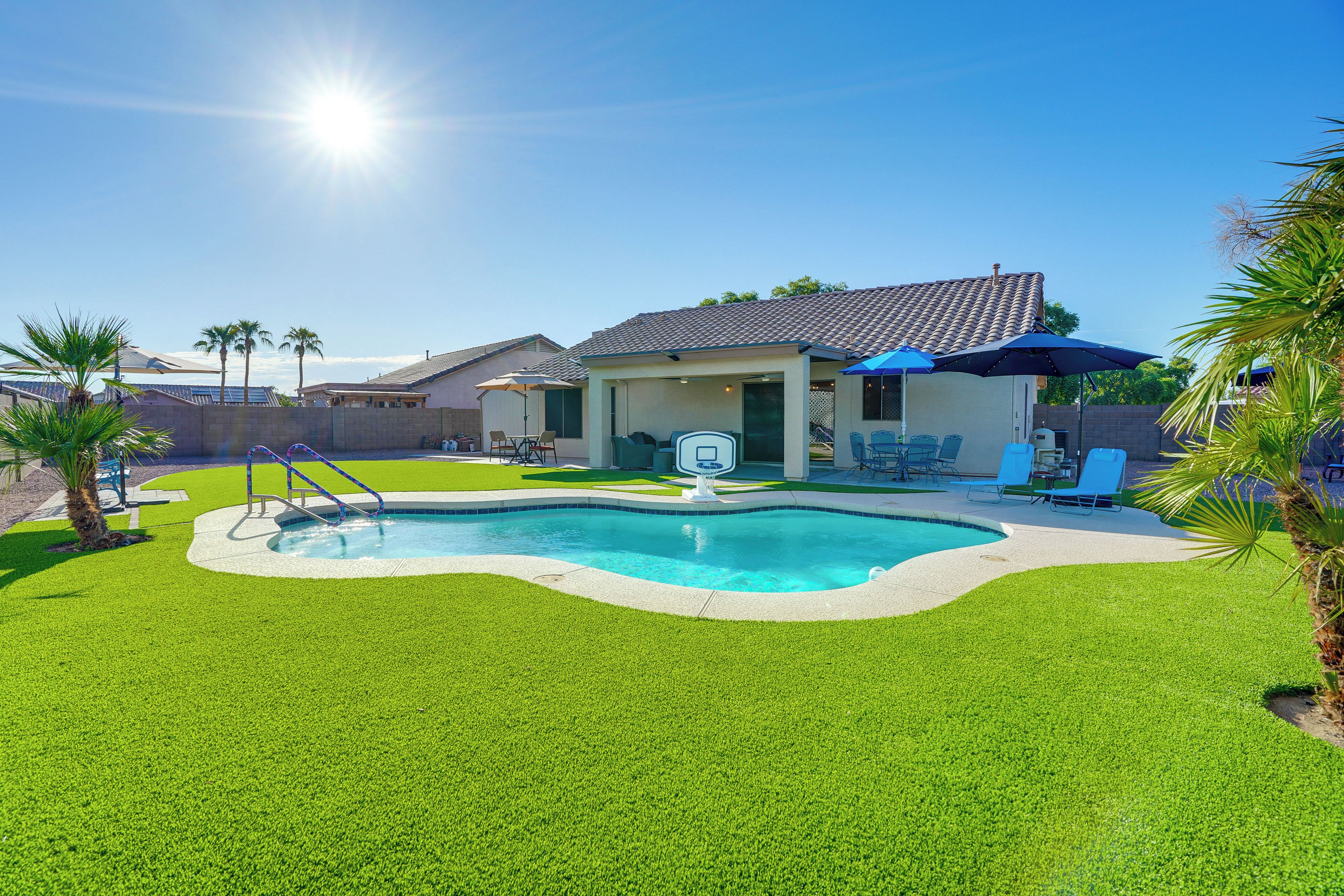 A backyard with a swimming pool, a covered patio, and a house.