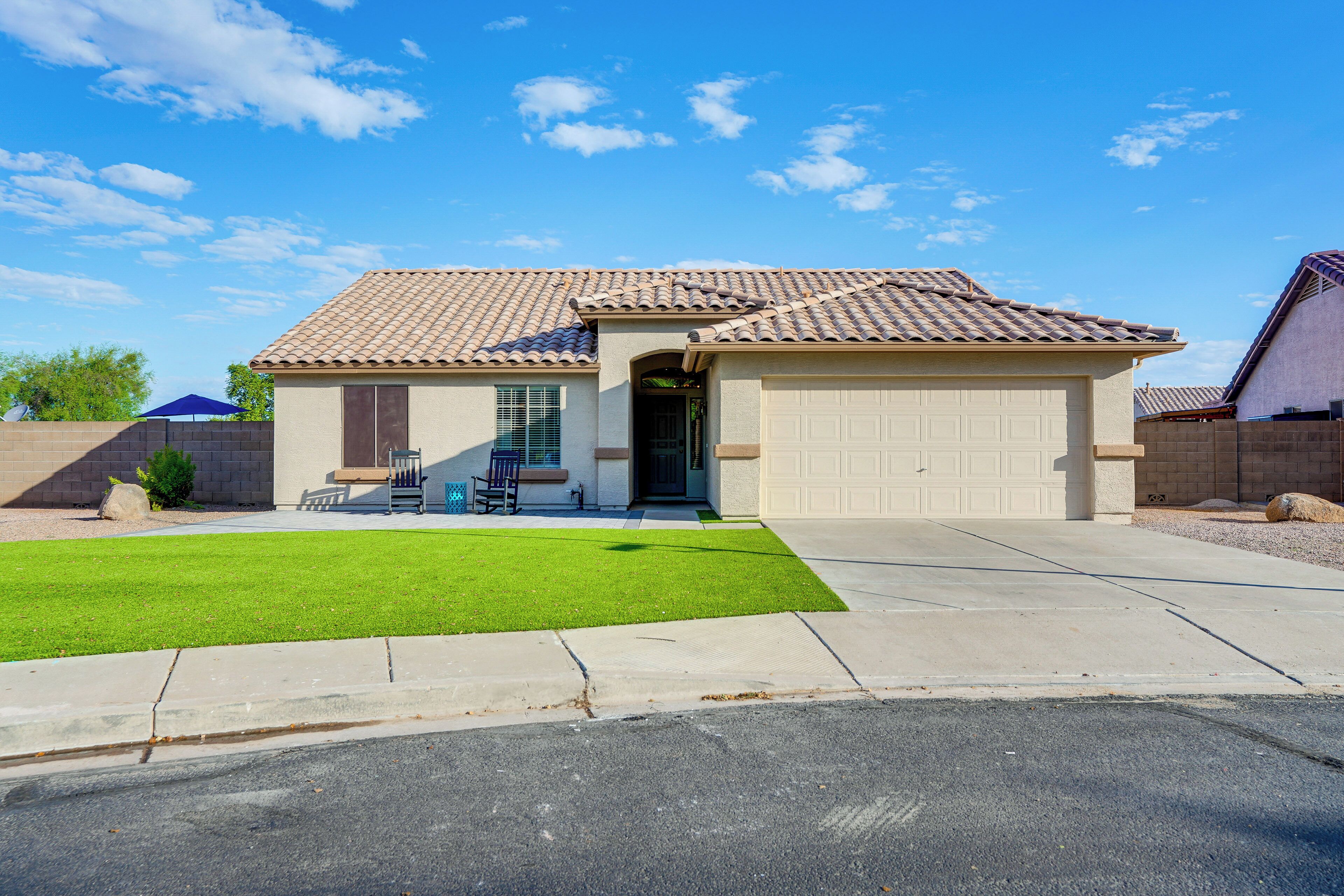 A residential house with a tiled roof, a garage, and a well-maintained lawn.