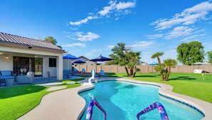 Ein Pool mit geschwungener Kante, umgeben von einem gepflegten Rasen und Palmen.