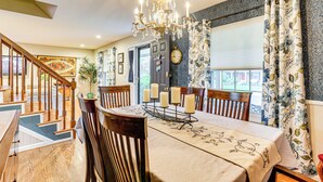 A dining area with a chandelier, wooden chairs, a table with candles, and a view of the outdoors through a window. - Spacious Family Home w/ Deck & Yard in Littleton! (Littleton)