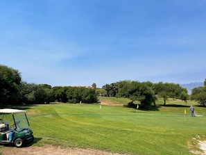 A golf course with a green cart, trees, and a clear sky. - Belvilla by Oyo Luxury Tropicana Club (Roquetas de Mar)