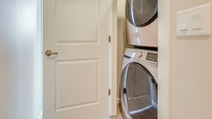 A laundry room with a closed door, a washing machine, and a dryer stacked on top of each other. - Home Base w/ Easy 1-80 Access: 4 Mi to Dtwn Reno! (Reno)