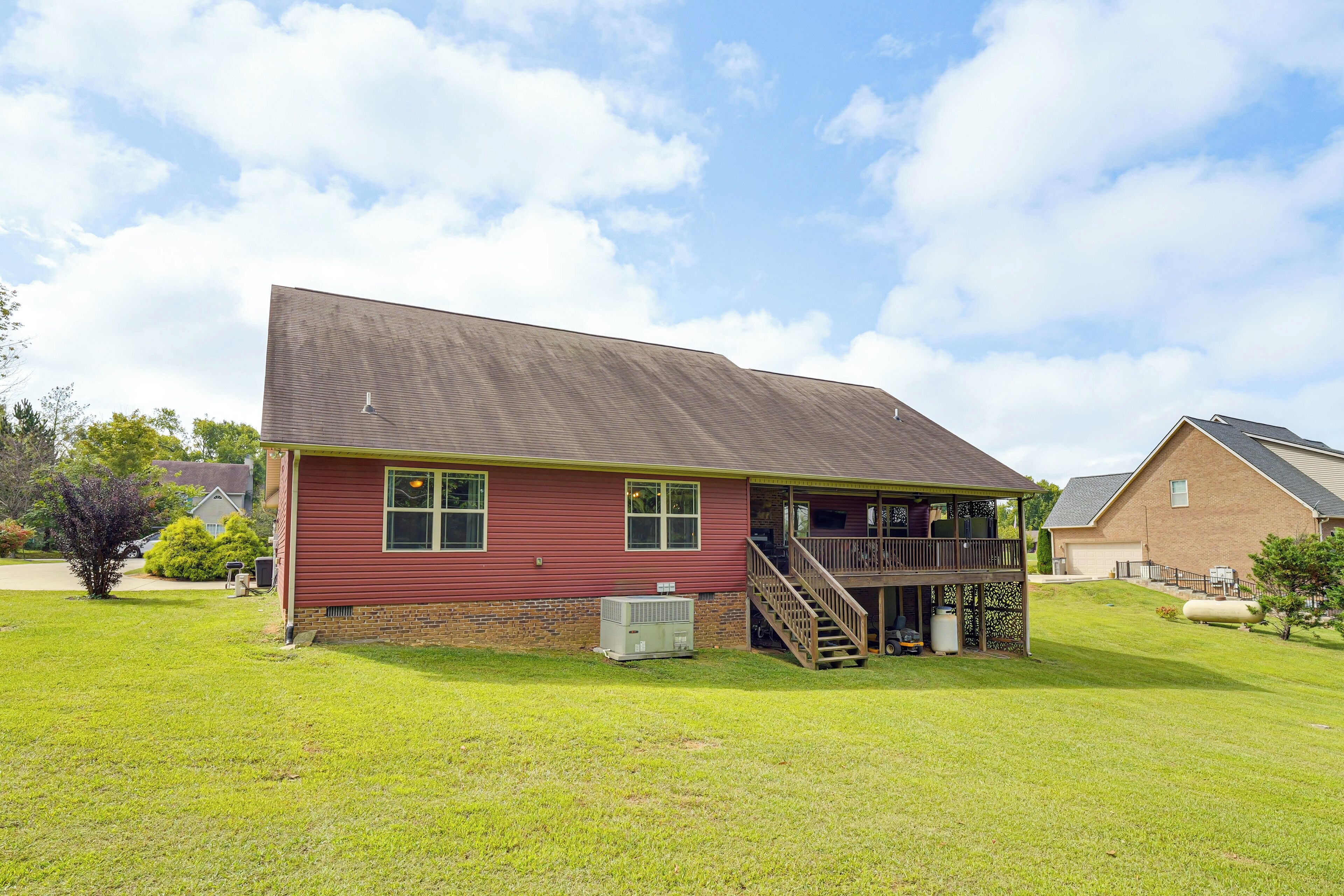 A two-story house with a red exterior, a wooden deck, and a staircase leading to the second floor.