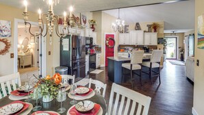 Une cuisine spacieuse dotée d’appareils électroménagers modernes, un coin repas agrémenté d’un lustre, et un salon confortable avec une cheminée.
