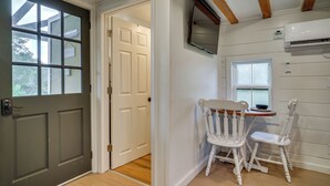 A room with a dark grey door, a white wall, a wooden ceiling, and a small table with two white chairs. - Cozy Couples Retreat w/ Porch on Bayou Teche! (New Iberia)