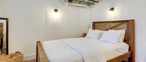 A bedroom with a wooden bed, white bedding, a woven basket, and a cowhide rug.