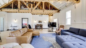 A spacious living room with a high ceiling, wooden beams, a large TV, and comfortable seating. - 'the Townhall' Northwoods Retreat w/ Large Patio! (Conover)