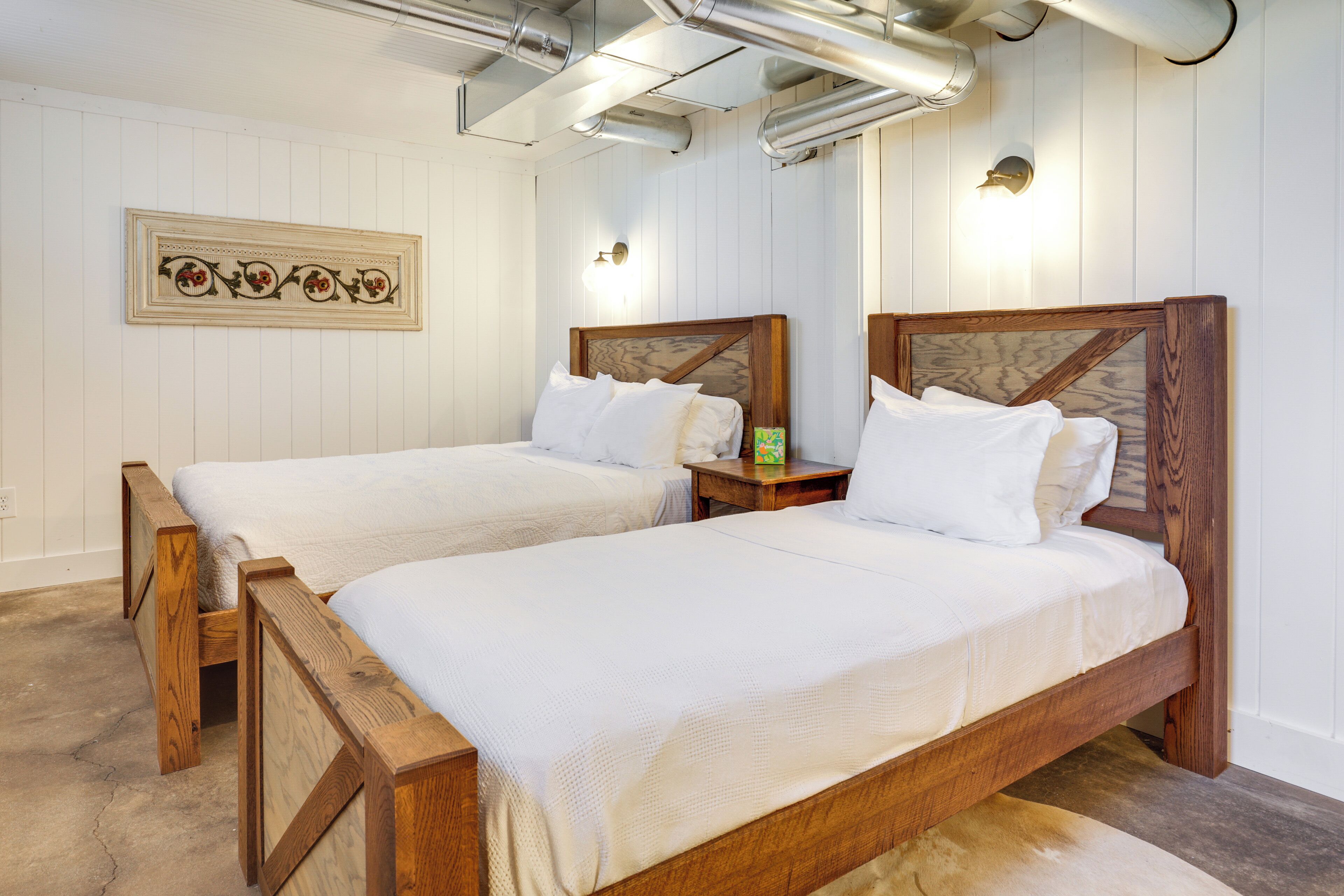 Une chambre à coucher avec deux lits en bois, une literie blanche et un élément décoratif mural.