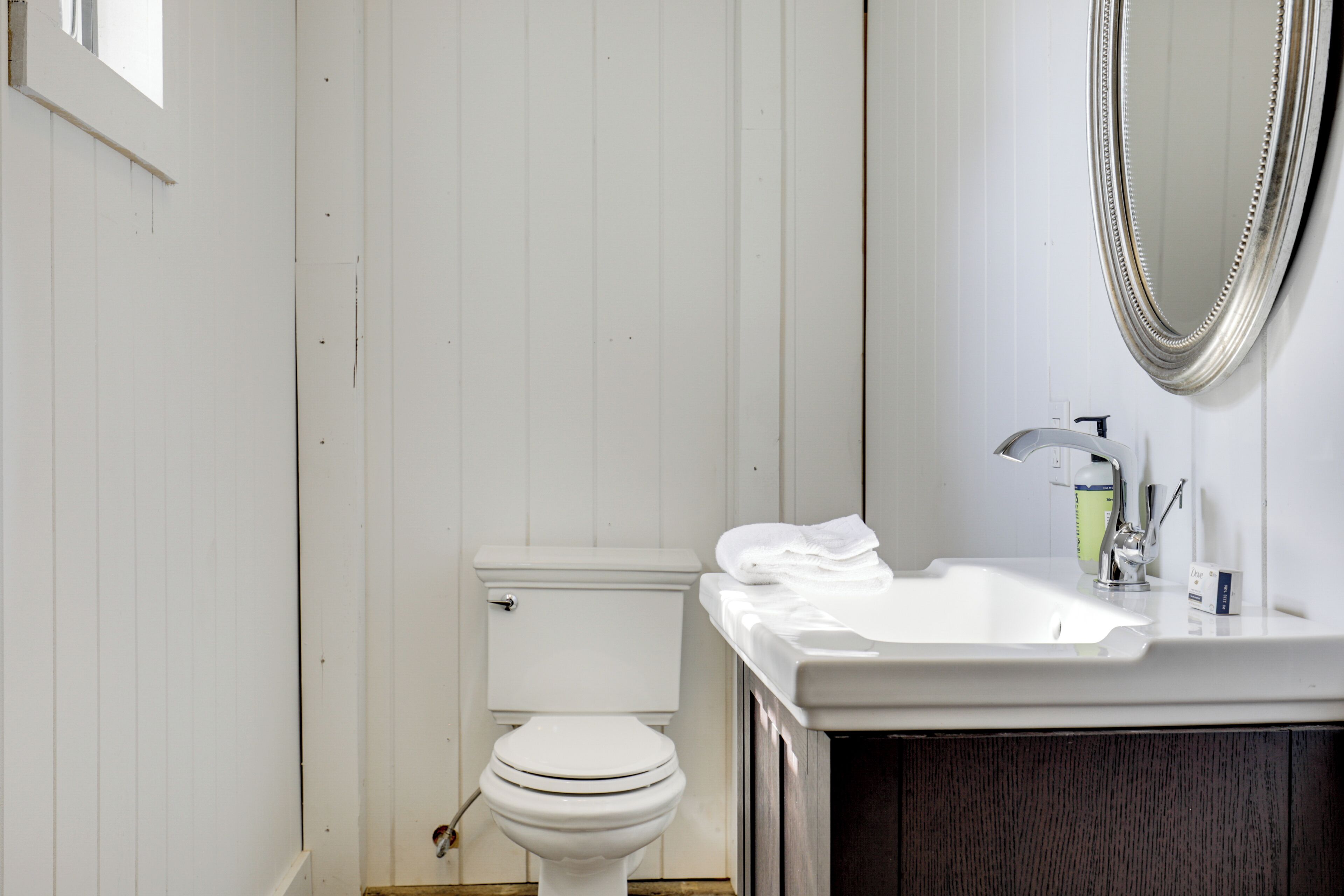 Un baño con inodoro blanco, lavamanos con espejo y armarios de madera.