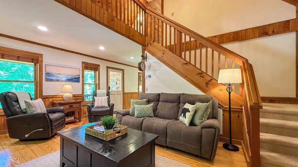A living room with a wooden staircase, leather recliner, brown sofa, and a coffee table. - Hot Tub, Fish, Ski: Outdoorsy Retreat in Boone! (Vilas)