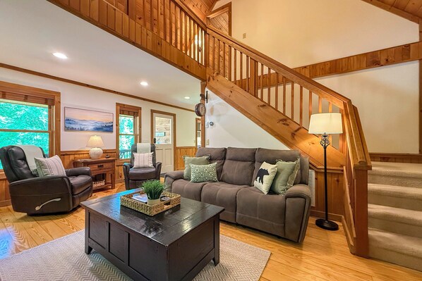 A living room with a wooden staircase, leather recliner, brown sofa, and a coffee table.