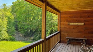 A wooden cabin with a balcony, a welcome sign, and a bench. - Hot Tub, Fish, Ski: Outdoorsy Retreat in Boone! (Vilas)